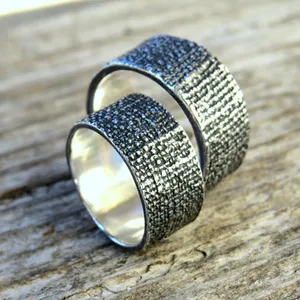 May include: Two silver rings with a textured surface. The rings are stacked on top of each other.