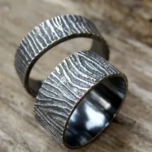 May include: Two silver rings with a textured woodgrain pattern. The rings are stacked on top of each other.