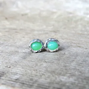 May include: A pair of silver earrings with green gemstone accents. The earrings have a textured, organic design.