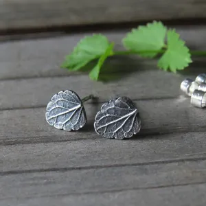 May include: A pair of silver leaf stud earrings. The earrings are made of metal and have a detailed leaf design.