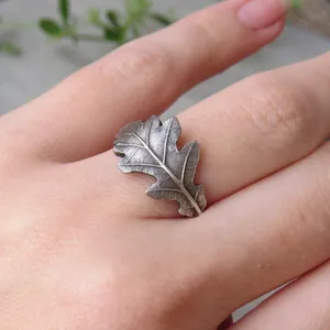 May include: A silver ring shaped like an oak leaf. The ring is detailed with veins and a textured surface.