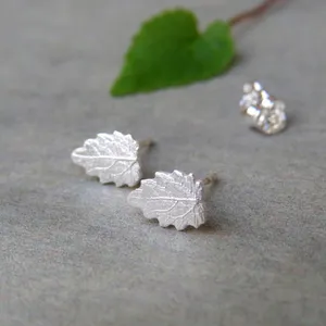 May include: A pair of silver leaf stud earrings. The leaves are detailed with veins and have a textured finish.