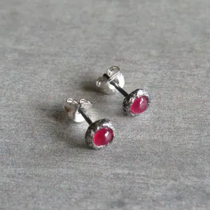 May include: A pair of silver stud earrings with a textured setting and a bright pink gemstone.