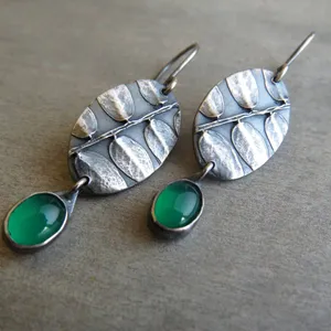 May include: Silver earrings with a leaf design and green gemstone accents.